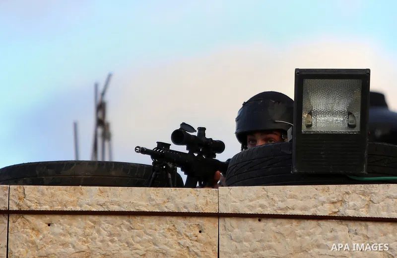 A member of Israeli security forces aims his weapon at Palestinian protesters during clashes in Jalazoun refugee camp near the West Bank city of Ramallah on Jan. 15, 2016. Photo by Shadi Hatem