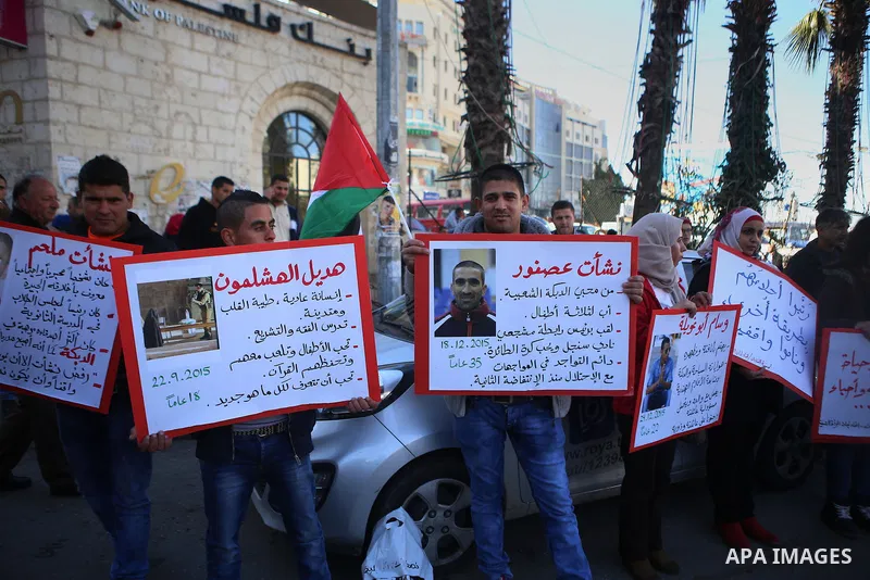 Palestinians from a human chain hold banners during a rally to show solidarity with the Palestine’s martyrs of the Intifada Jerusalem , in the West Bank city of Ramallah, on January 16, 2016. This has brought the number...