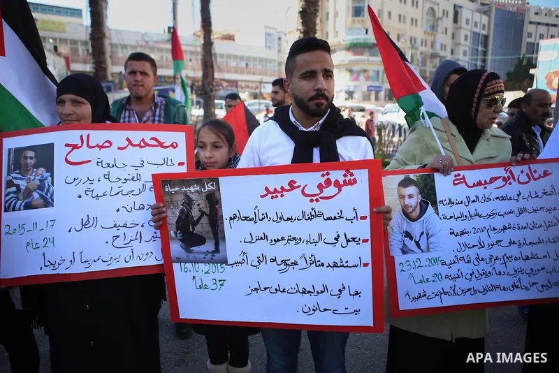 Palestinians from a human chain hold banners during a rally to show solidarity with the Palestine’s martyrs of the Intifada Jerusalem , in the West Bank city of Ramallah, on January 16, 2016. This has brought the number...