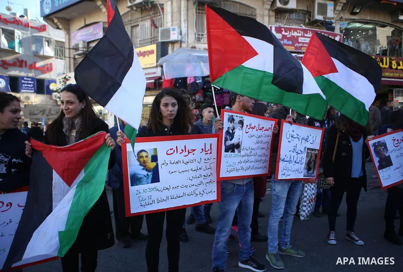 Palestinians from a human chain hold banners during a rally to show solidarity with the Palestine’s martyrs of the Intifada Jerusalem , in the West Bank city of Ramallah, on January 16, 2016. This has brought the number...