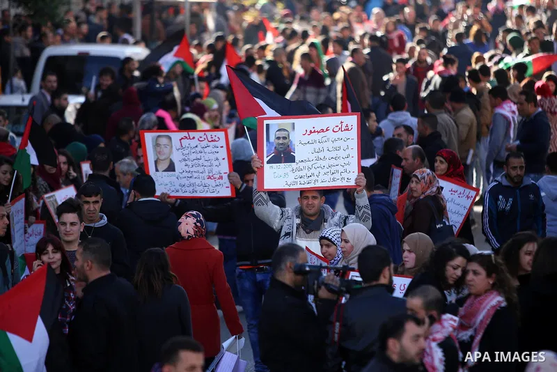 Palestinians from a human chain hold banners during a rally to show solidarity with the Palestine’s martyrs of the Intifada Jerusalem , in the West Bank city of Ramallah, on January 16, 2016. This has brought the number...