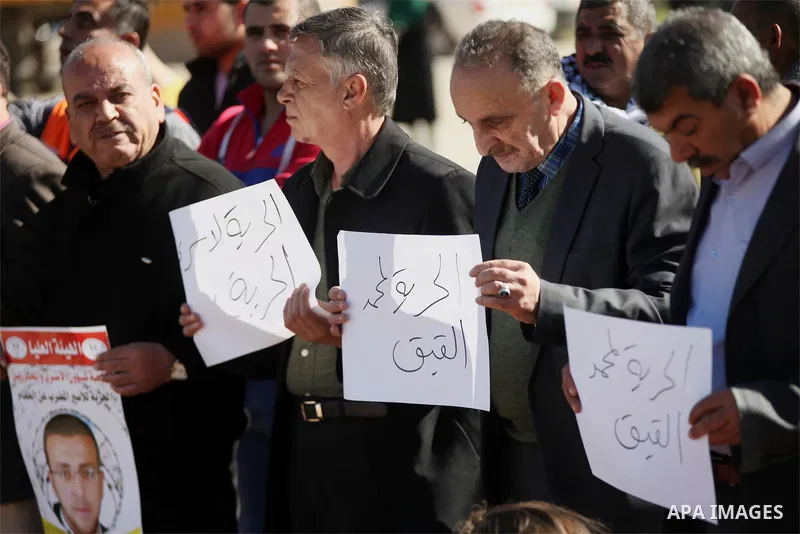 Palestinians take part in a demonstration demanding the release of Palestinian journalist Mohammed al-Qiq from Israeli jails, outside the compound of the Israeli Ofer Military prison, near the West Bank city of Ramallah,...
