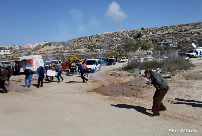 Palestinian take cover from tear gas fired by Israeli security forces following a demonstration demanding the release of Palestinian journalist Mohammed al-Qiq from Israeli jails, outside the compound of the Israeli Ofer...
