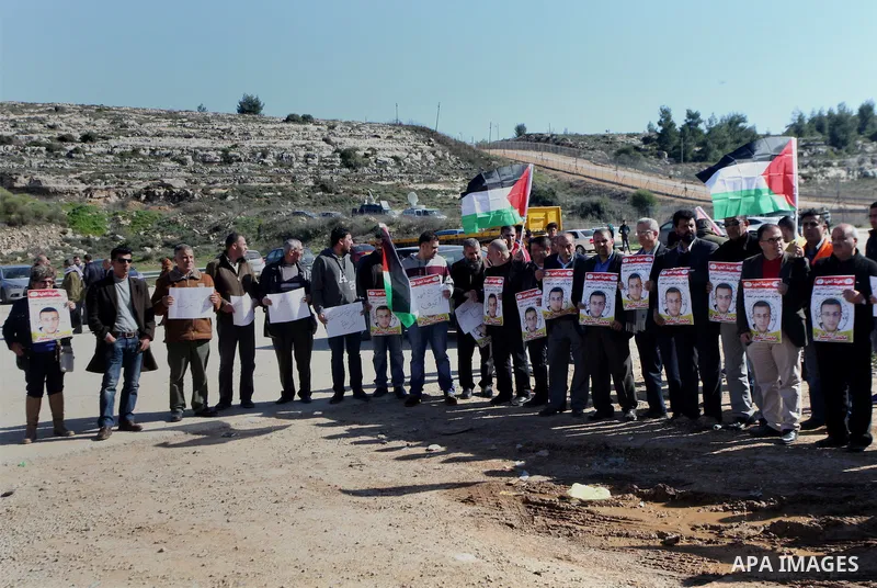 Palestinians take part in a demonstration demanding the release of Palestinian journalist Mohammed al-Qiq from Israeli jails, outside the compound of the Israeli Ofer Military prison, near the West Bank city of Ramallah,...