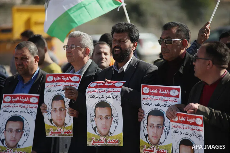 Palestinians take part in a demonstration demanding the release of Palestinian journalist Mohammed al-Qiq from Israeli jails, outside the compound of the Israeli Ofer Military prison, near the West Bank city of Ramallah,...