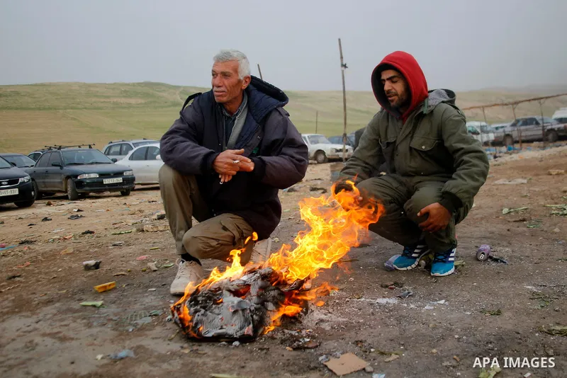 Palestinians working in Israel warm themselves by a fire as they wait to cross through the Israeli-controlled Mitar checkpoint south of the West Bank city of Hebron January 19, 2016. Photo by Wisam Hashlamoun