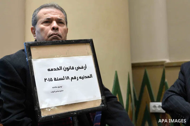 Tawfiq Okasha, a pro-government TV anchorman who was elected to parliament, sits in an anteroom and holds banners against Civil Service Law during a parliamentary session, in Cairo, Egypt in Jan. 19, 2016. Photo by Amr S...