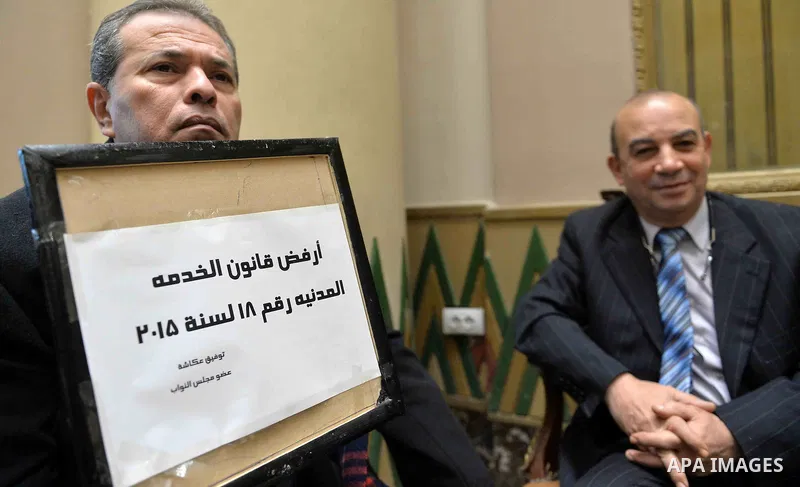 Tawfiq Okasha, a pro-government TV anchorman who was elected to parliament, sits in an anteroom and holds banners against Civil Service Law during a parliamentary session, in Cairo, Egypt in Jan. 19, 2016. Photo by Amr S...