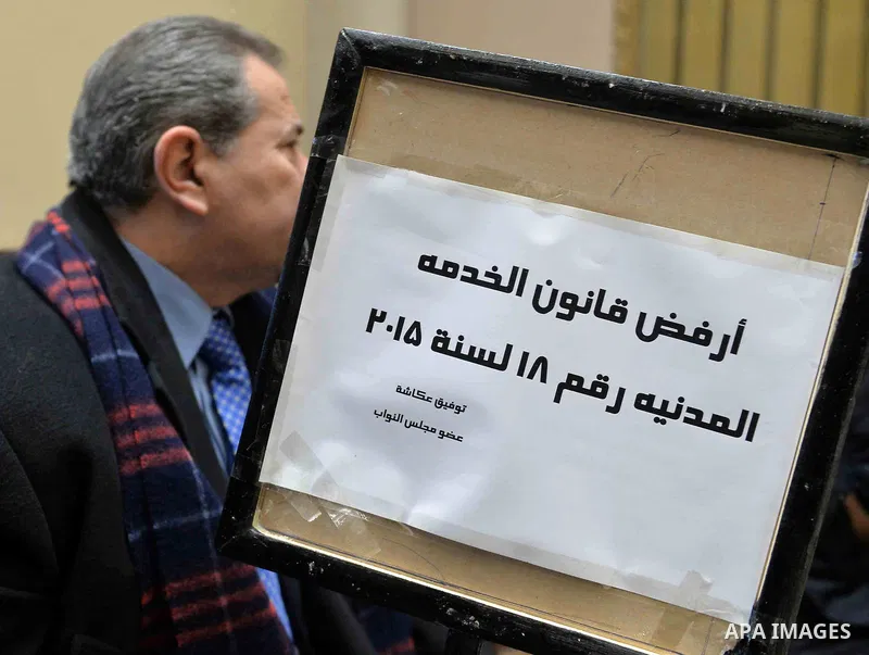 Tawfiq Okasha, a pro-government TV anchorman who was elected to parliament, sits in an anteroom and holds banners against Civil Service Law during a parliamentary session, in Cairo, Egypt in Jan. 19, 2016. Photo by Amr S...