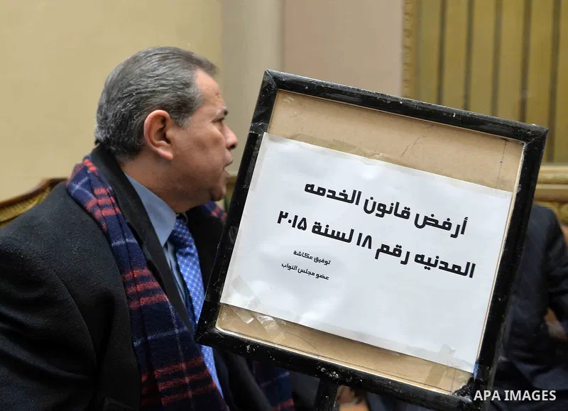Tawfiq Okasha, a pro-government TV anchorman who was elected to parliament, sits in an anteroom and holds banners against Civil Service Law during a parliamentary session, in Cairo, Egypt in Jan. 19, 2016. Photo by Amr S...
