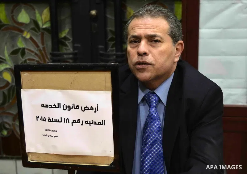 Tawfiq Okasha, a pro-government TV anchorman who was elected to parliament, sits in an anteroom and holds banners against Civil Service Law during a parliamentary session, in Cairo, Egypt in Jan. 19, 2016. Photo by Amr S...