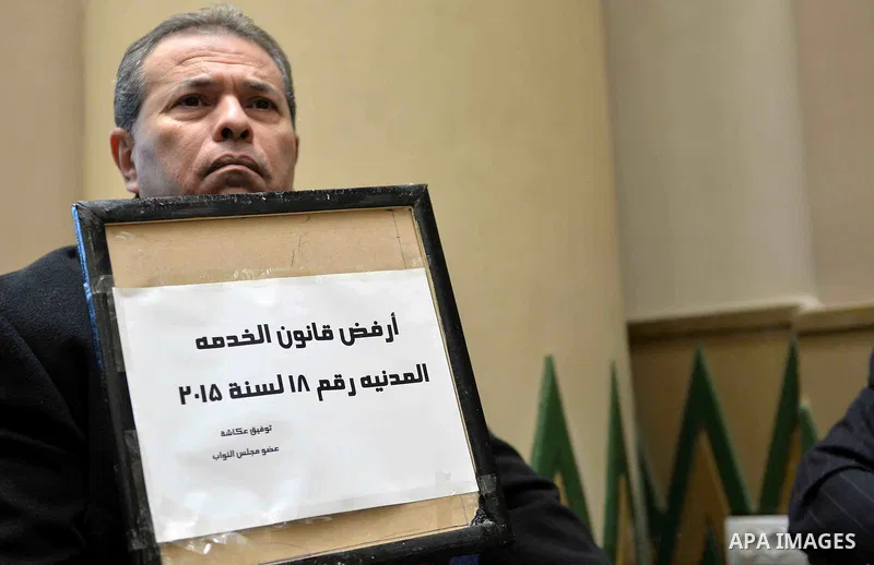 Tawfiq Okasha, a pro-government TV anchorman who was elected to parliament, sits in an anteroom and holds banners against Civil Service Law during a parliamentary session, in Cairo, Egypt in Jan. 19, 2016. Photo by Amr S...
