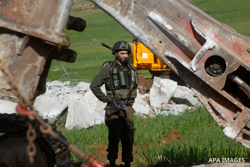An Israeli border policeman stands guard during the demolition of a Palestinian house under the order of the Israeli army, in the West Bank town of Dura, south of Hebron January 20, 2016. The owners of the house said the...