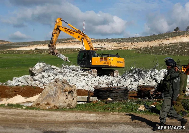 An Israeli border policeman stands guard during the demolition of a Palestinian house under the order of the Israeli army, in the West Bank town of Dura, south of Hebron January 20, 2016. The owners of the house said the...