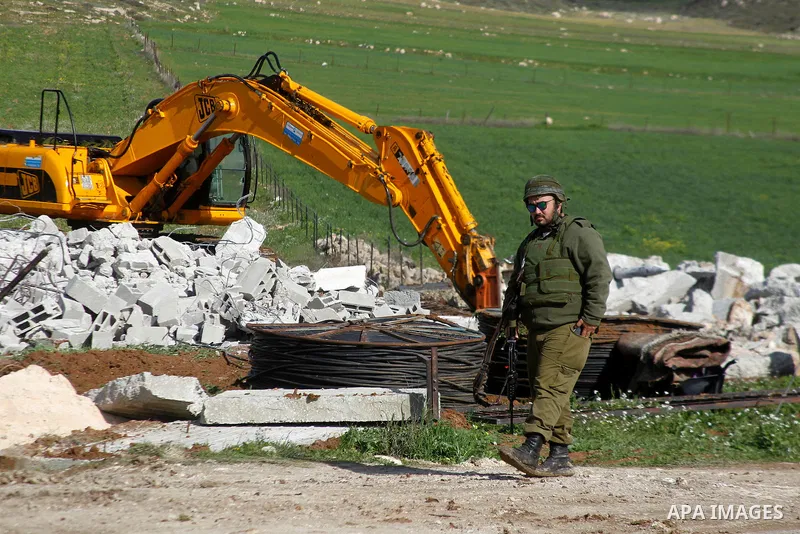 An Israeli border policeman stands guard during the demolition of a Palestinian house under the order of the Israeli army, in the West Bank town of Dura, south of Hebron January 20, 2016. The owners of the house said the...