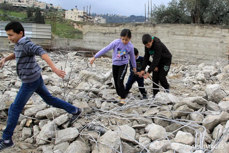 Palestinian children walk on the rubbles of thier family house that was demolished after Israeli authorities said it was built without a permit in Wadi Qaddum in the East Jerusalem neighborhood of Silwan on Jan. 20, 2016...