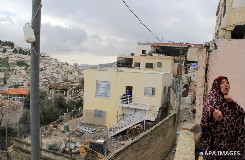 A Palestinian woman looks on during Israeli settlers sit on the balcony of house which the Palestinian Abu Tir family has for years that was taken over by Israeli settlers backed by police in the East Jerusalem neighbour...