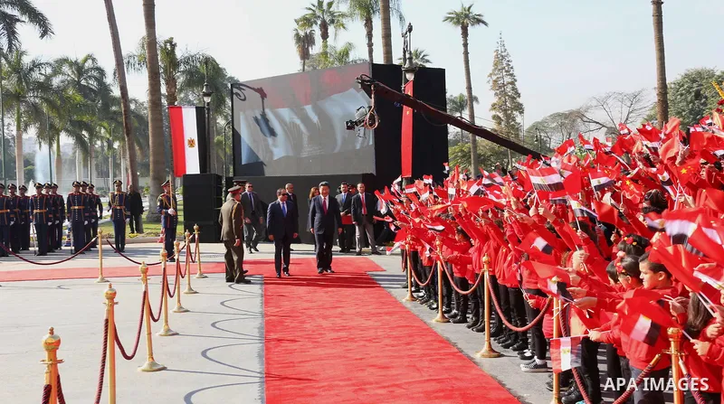 Children carrying Chinese flags cheer as Egyptian President Abdel Fattah al-Sisi (L) walks with Chinese President Xi Jinping (R) at the presidential palace during their meeting in Cairo, Egypt, January 21, 2016, in this...