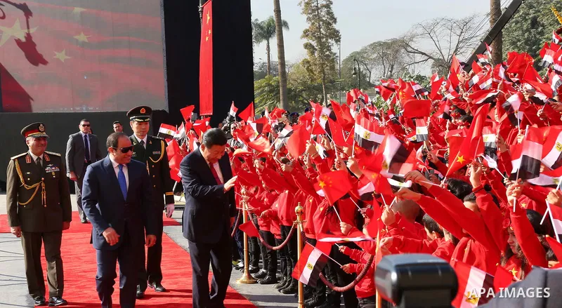Children carrying Chinese flags cheer as Egyptian President Abdel Fattah al-Sisi (L) walks with Chinese President Xi Jinping (R) at the presidential palace during their meeting in Cairo, Egypt, January 21, 2016, in this...