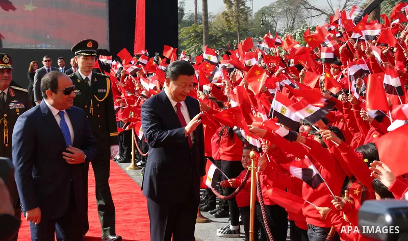 Children carrying Chinese flags cheer as Egyptian President Abdel Fattah al-Sisi (L) walks with Chinese President Xi Jinping (R) at the presidential palace during their meeting in Cairo, Egypt, January 21, 2016, in this...