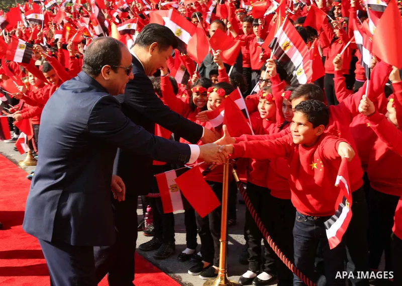 Children carrying Chinese flags cheer as Egyptian President Abdel Fattah al-Sisi (L) walks with Chinese President Xi Jinping (R) at the presidential palace during their meeting in Cairo, Egypt, January 21, 2016, in this...