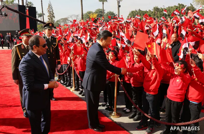 Children carrying Chinese flags cheer as Egyptian President Abdel Fattah al-Sisi (L) walks with Chinese President Xi Jinping (R) at the presidential palace during their meeting in Cairo, Egypt, January 21, 2016, in this...