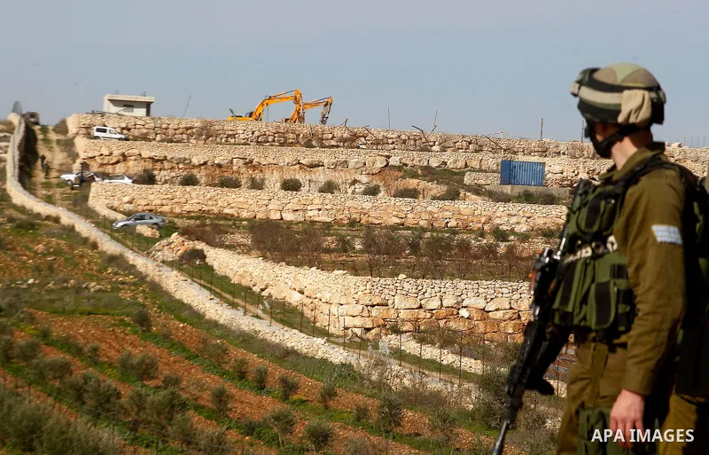 An Israeli soldier stands guard during the demolition of a Palestinian house at the order of the Israeli army in the West Bank village of Biet Ula, west of Hebron January 21, 2016. The owners of the house said they were...