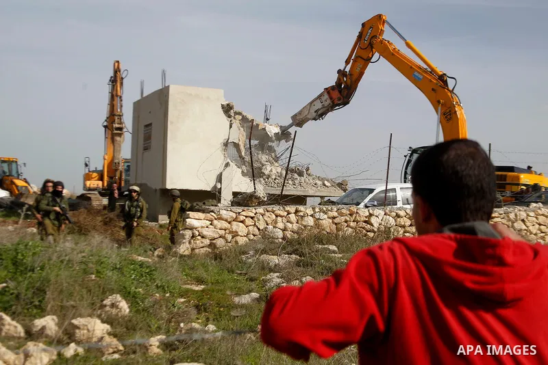 A Palestinian man watchs the demolition of a Palestinian house at the order of the Israeli army in the West Bank village of Biet Ula, west of Hebron January 21, 2016. The owners of the house said they were informed by th...