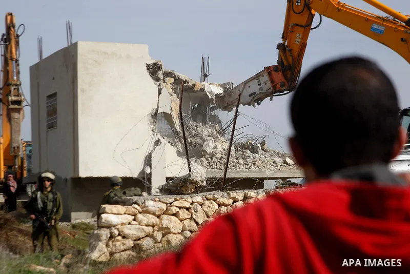 A Palestinian man watchs the demolition of a Palestinian house at the order of the Israeli army in the West Bank village of Biet Ula, west of Hebron January 21, 2016. The owners of the house said they were informed by th...