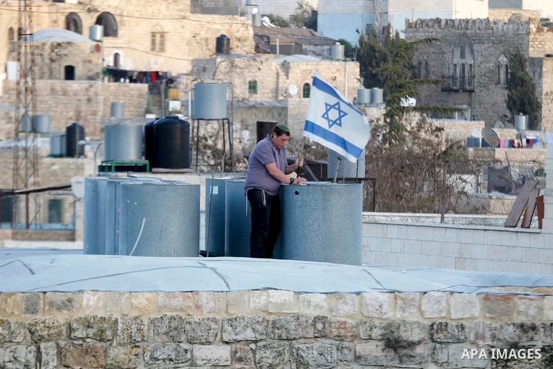 An Israeli settler puts an Israeli flag on the roof of a Palestinian house in a building in the centre of the Palestinian city Hebron, sparking violent clashes amid a disputed claim of ownership, witnesses said on Januar...