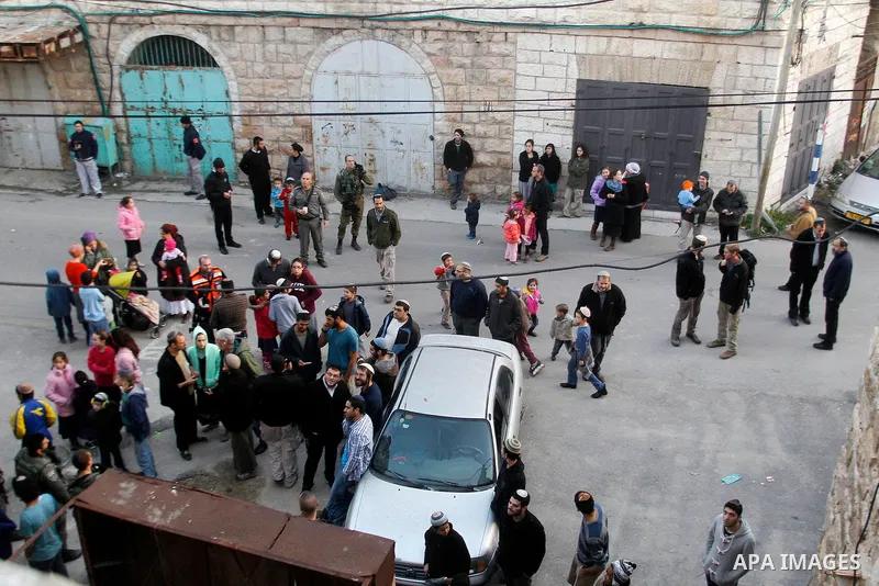 Israeli sttlers under the escort of Israeli border police gather outside two homes in a building in the centre of the Palestinian city Hebron, sparking violent clashes amid a disputed claim of ownership, witnesses said o...