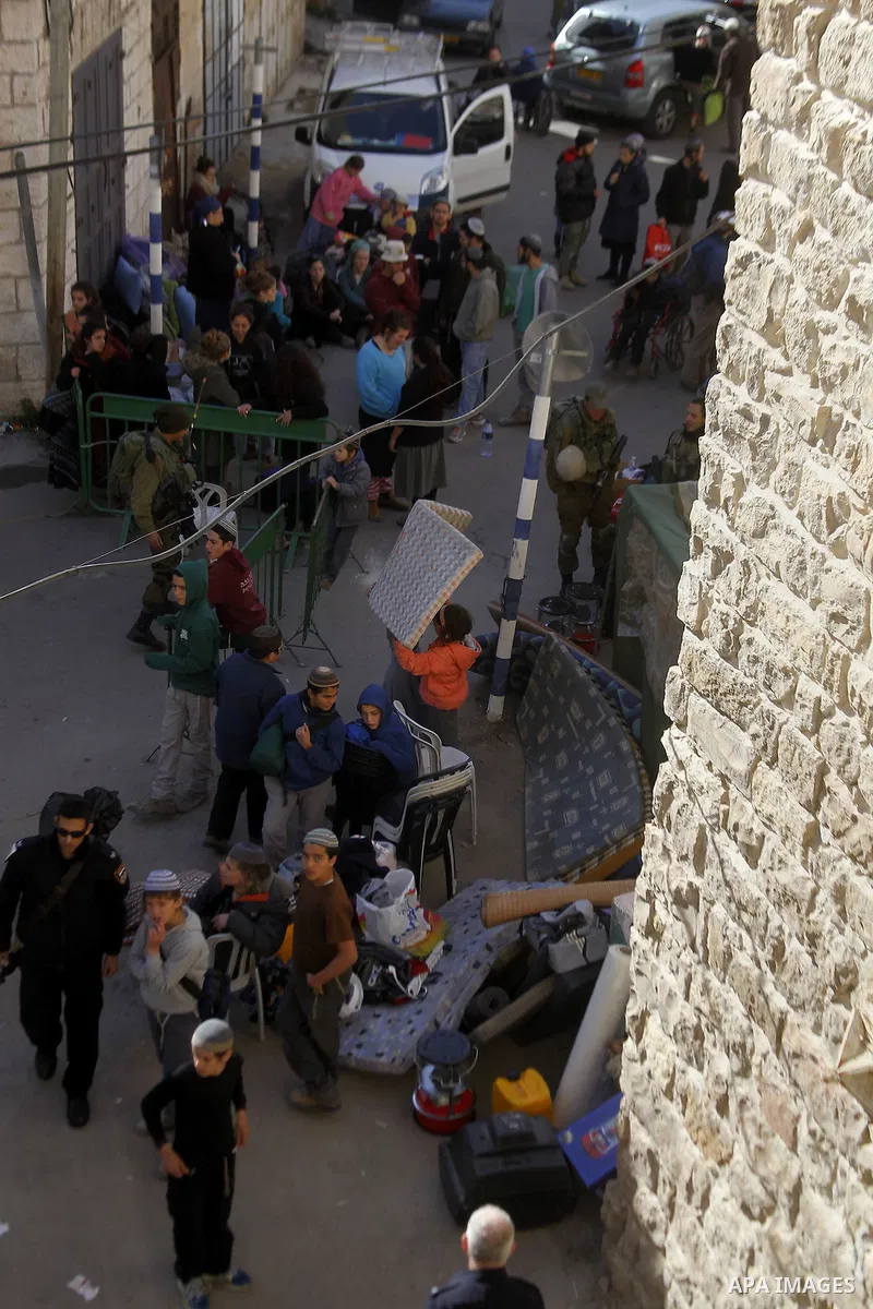 Jewish settlers collect their belongings as dozens of settlers were evacuated by Israeli security forces from two homes in the heart of the West Bank city of Hebron on January 22, 2016, the day after they entered the bui...