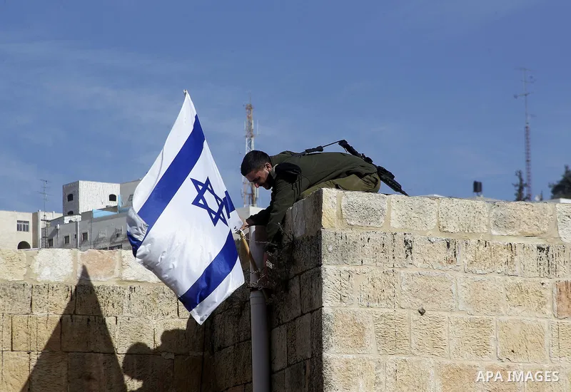 An Israeli soldier removes the Israeli flag from a house as dozens of settlers were evacuated by Israeli security forces from two homes in the heart of the West Bank city of Hebron on January 22, 2016, the day after they...