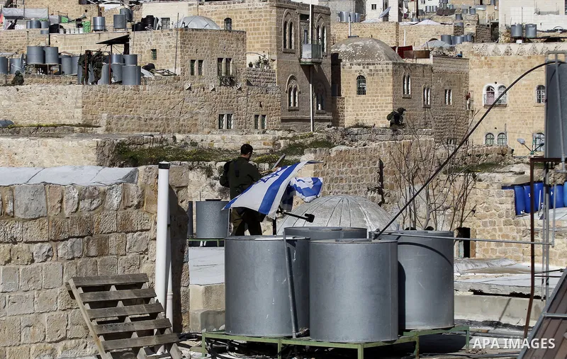 An Israeli soldier removes the Israeli flag from a house as dozens of settlers were evacuated by Israeli security forces from two homes in the heart of the West Bank city of Hebron on January 22, 2016, the day after they...