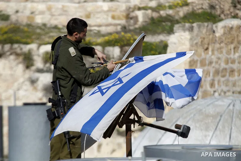 An Israeli soldier removes the Israeli flag from a house as dozens of settlers were evacuated by Israeli security forces from two homes in the heart of the West Bank city of Hebron on January 22, 2016, the day after they...