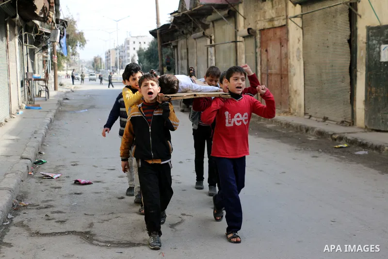 Syrian children carry the body of their friend as they play in a symbolic funeral in the northern Syrian city of Aleppo, on Jan. 22, 2016. Photo by Ameer al-Halbi
