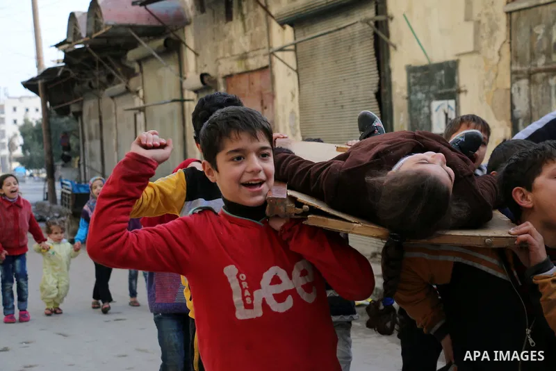 Syrian children carry the body of their friend as they play in a symbolic funeral in the northern Syrian city of Aleppo, on Jan. 22, 2016. Photo by Ameer al-Halbi