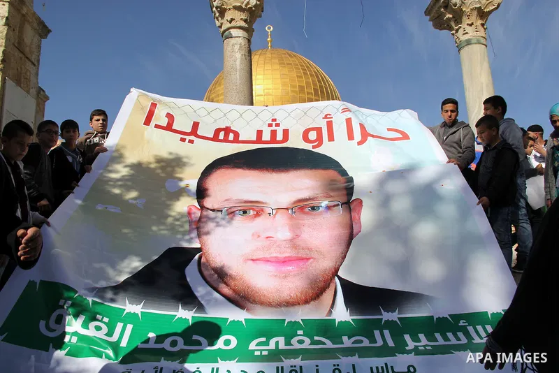 Palestinians take part in a demonstration demanding the release of Palestinian journalist Mohammed al-Qiq (portrait) from Israeli jails, in front of Jerusalem's Dome of the Rock mosque at the Al-Aqsa mosque compound on J...