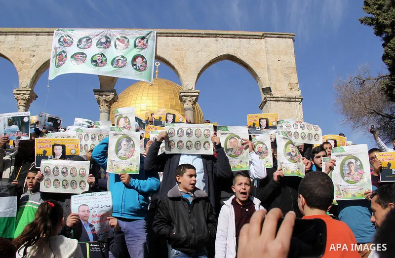 Palestinians carry placards bearing the portraits of 10 reported Palestinian attackers, whose bodies are still under Israeli custody, during a demonstration demanding the release of the bodies and the release of Palestin...