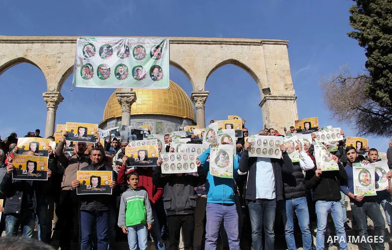 Palestinians carry placards bearing the portraits of 10 reported Palestinian attackers, whose bodies are still under Israeli custody, during a demonstration demanding the release of the bodies and the release of Palestin...