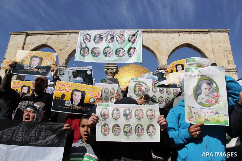Palestinians carry placards bearing the portraits of 10 reported Palestinian attackers, whose bodies are still under Israeli custody, during a demonstration demanding the release of the bodies and the release of Palestin...