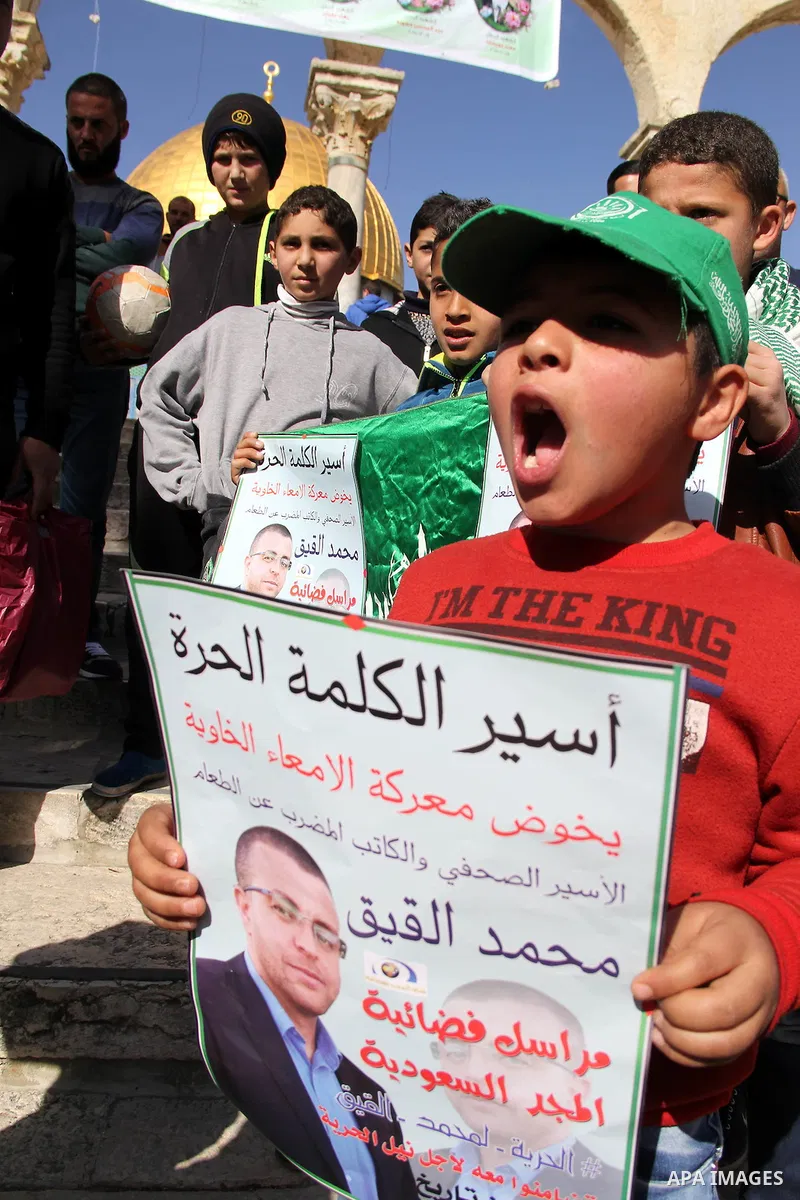 Palestinians take part in a demonstration demanding the release of Palestinian journalist Mohammed al-Qiq (portrait) from Israeli jails, in front of Jerusalem's Dome of the Rock mosque at the Al-Aqsa mosque compound on J...