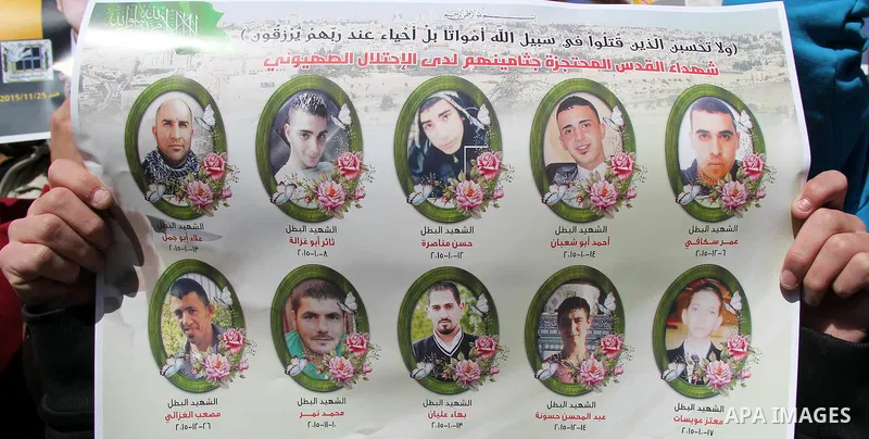 Palestinians carry placards bearing the portraits of 10 reported Palestinian attackers, whose bodies are still under Israeli custody, during a demonstration demanding the release of the bodies and the release of Palestin...