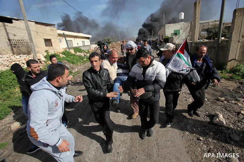 Palestinians carry a wounded protester during clashes with Israeli security forces following a protest against the expropriation of Palestinian land by Israel in the West Bank village of Kafr Qaddum, near the northern ci...