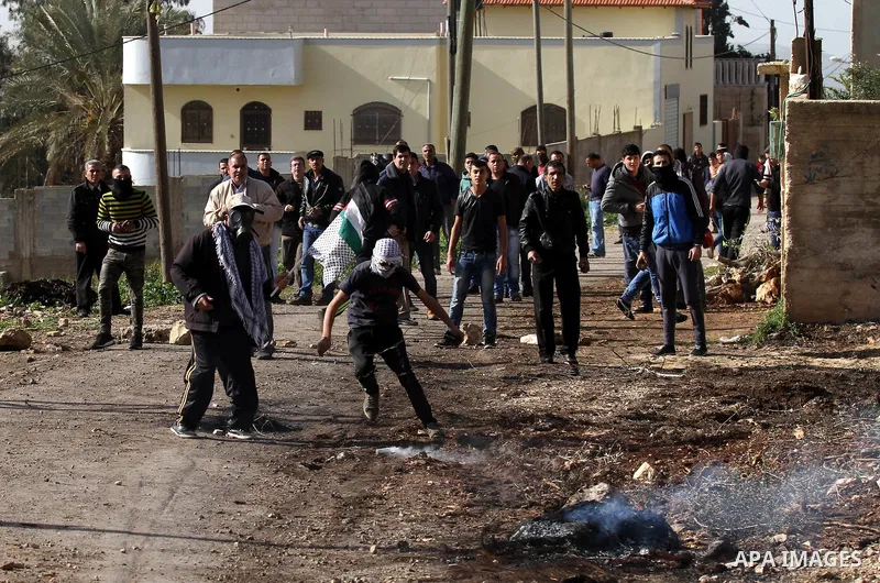 A Palestinian protester uses a slingshot to throw back a canisters fired by Israeli secrity forces during clashes following a protest against the expropriation of Palestinian land by Israel in the West Bank village of Ka...