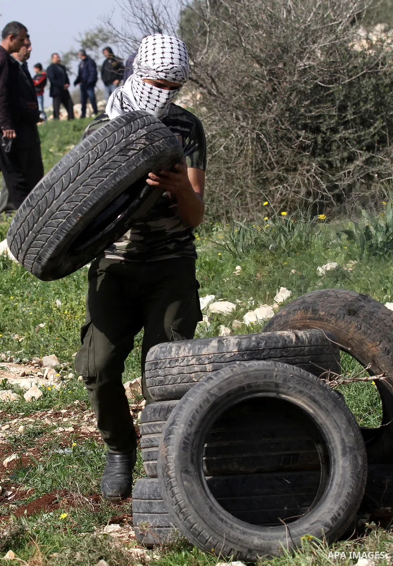 A Palestinian protester carries tires during clashes with Israeli security forces following a protest against the expropriation of Palestinian land by Israel in the West Bank village of Kafr Qaddum, near the northern cit...