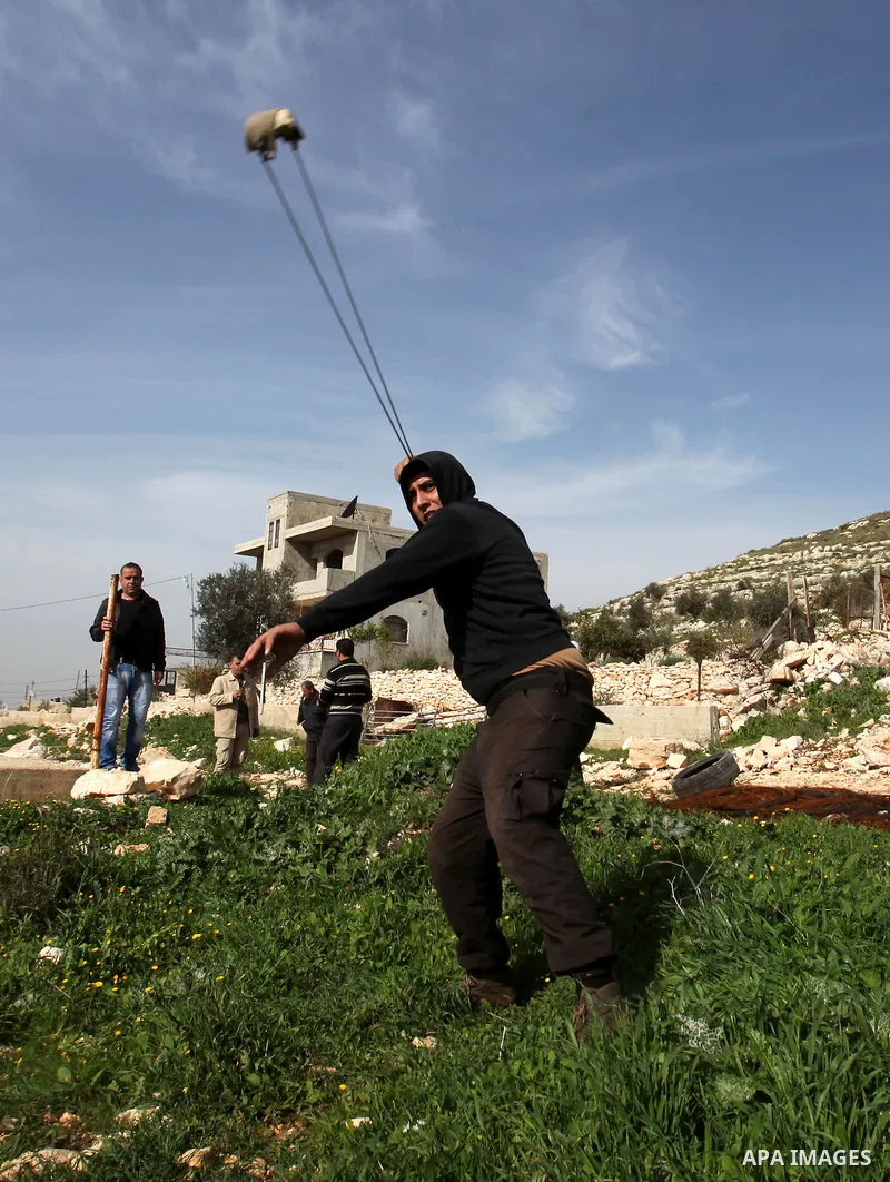 A Palestinian protester hurls stones toward Israeli security forces during clashes following a protest against the expropriation of Palestinian land by Israel in the West Bank village of Kafr Qaddum, near the northern ci...