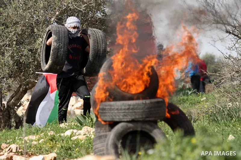 A Palestinian protester carries tires during clashes with Israeli security forces following a protest against the expropriation of Palestinian land by Israel in the West Bank village of Kafr Qaddum, near the northern cit...