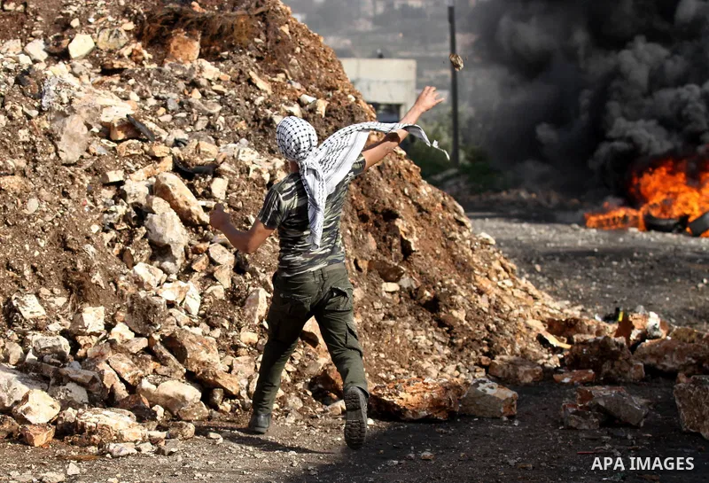 A Palestinian protester hurls stones toward Israeli security forces during clashes following a protest against the expropriation of Palestinian land by Israel in the West Bank village of Kafr Qaddum, near the northern ci...