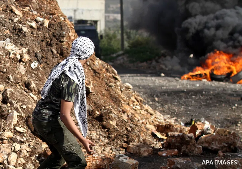 A Palestinian protester hurls stones toward Israeli security forces during clashes following a protest against the expropriation of Palestinian land by Israel in the West Bank village of Kafr Qaddum, near the northern ci...